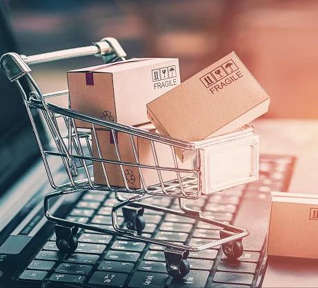 Mini shopping cart filled with small cardboard boxes on a laptop keyboard.